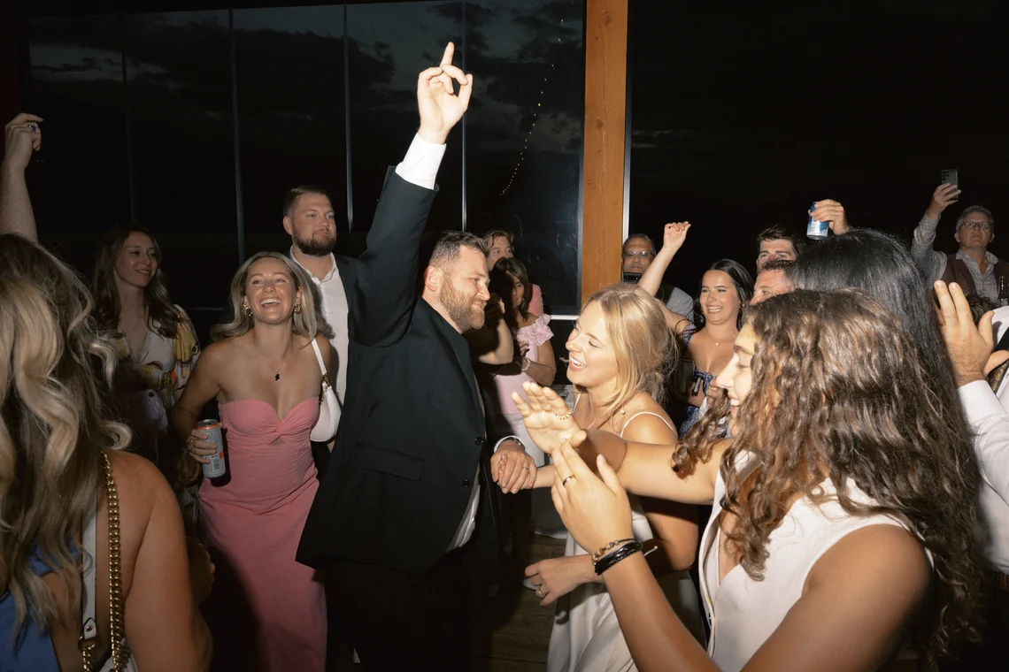 A full wedding dance floor at the peak of the after-party, hands raised, at a Fraser Valley reception.